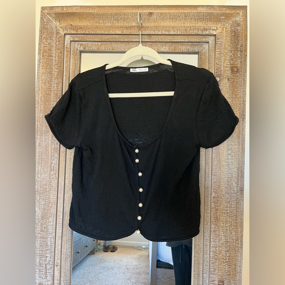 Black tshirt with white buttons in front. Size L.